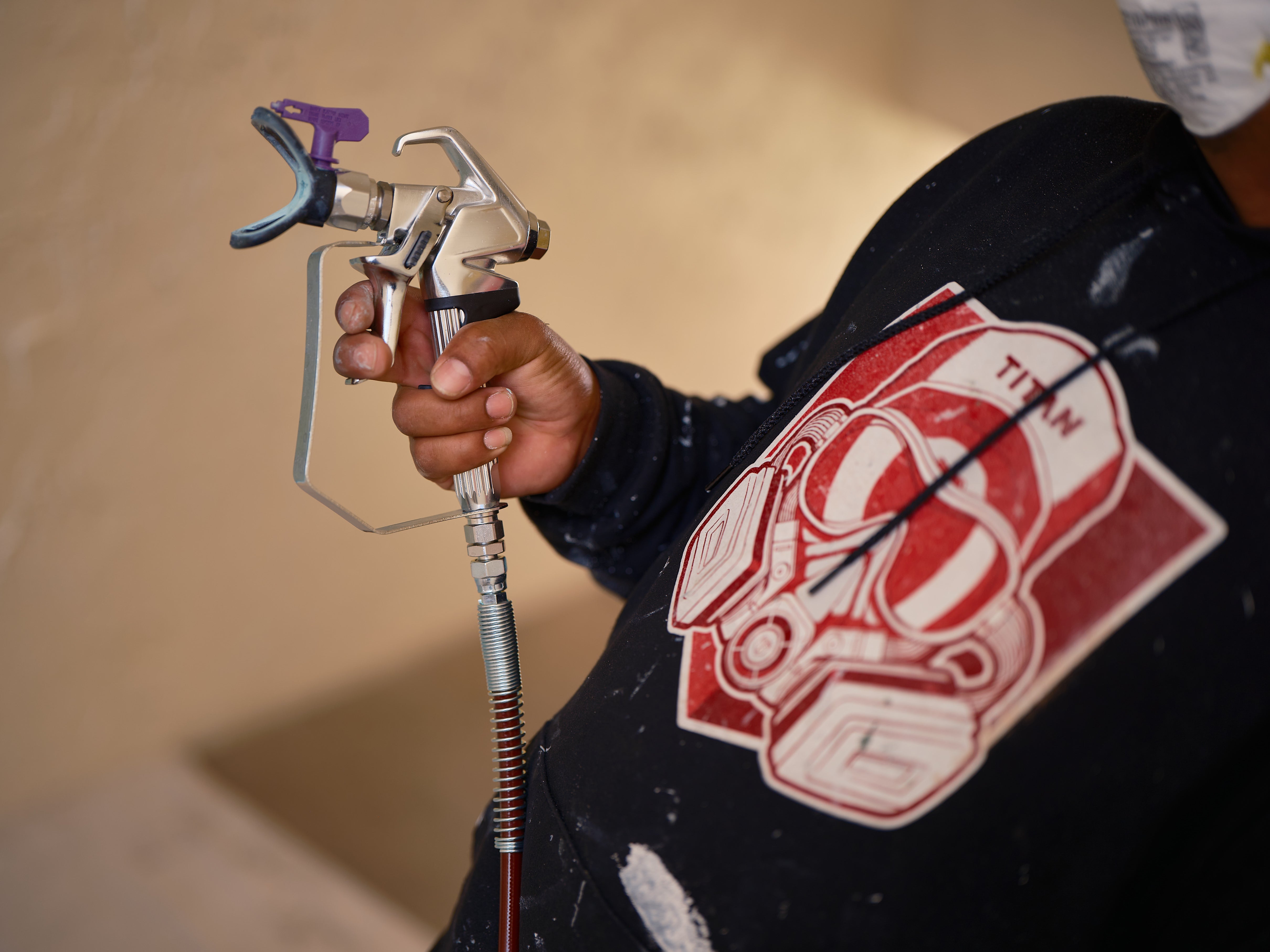 Pistolet airless TITAN équipé d'une buse Fine Finish violette et de son porte-buse sur un chantier de finition